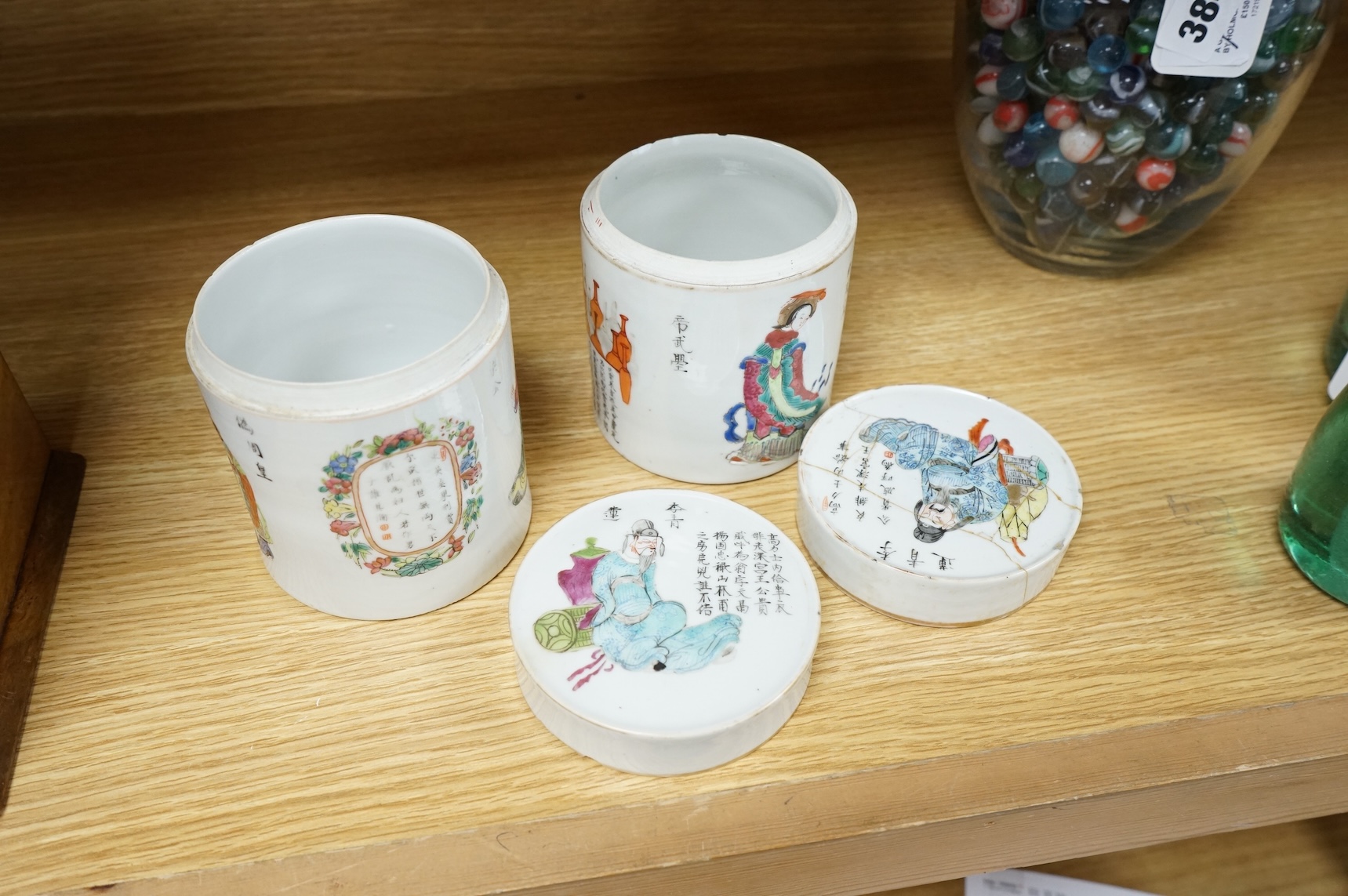 Two mid-19th century Chinese famille rose cylindrical jars and covers, enamelled with figures and calligraphy, 12cm high